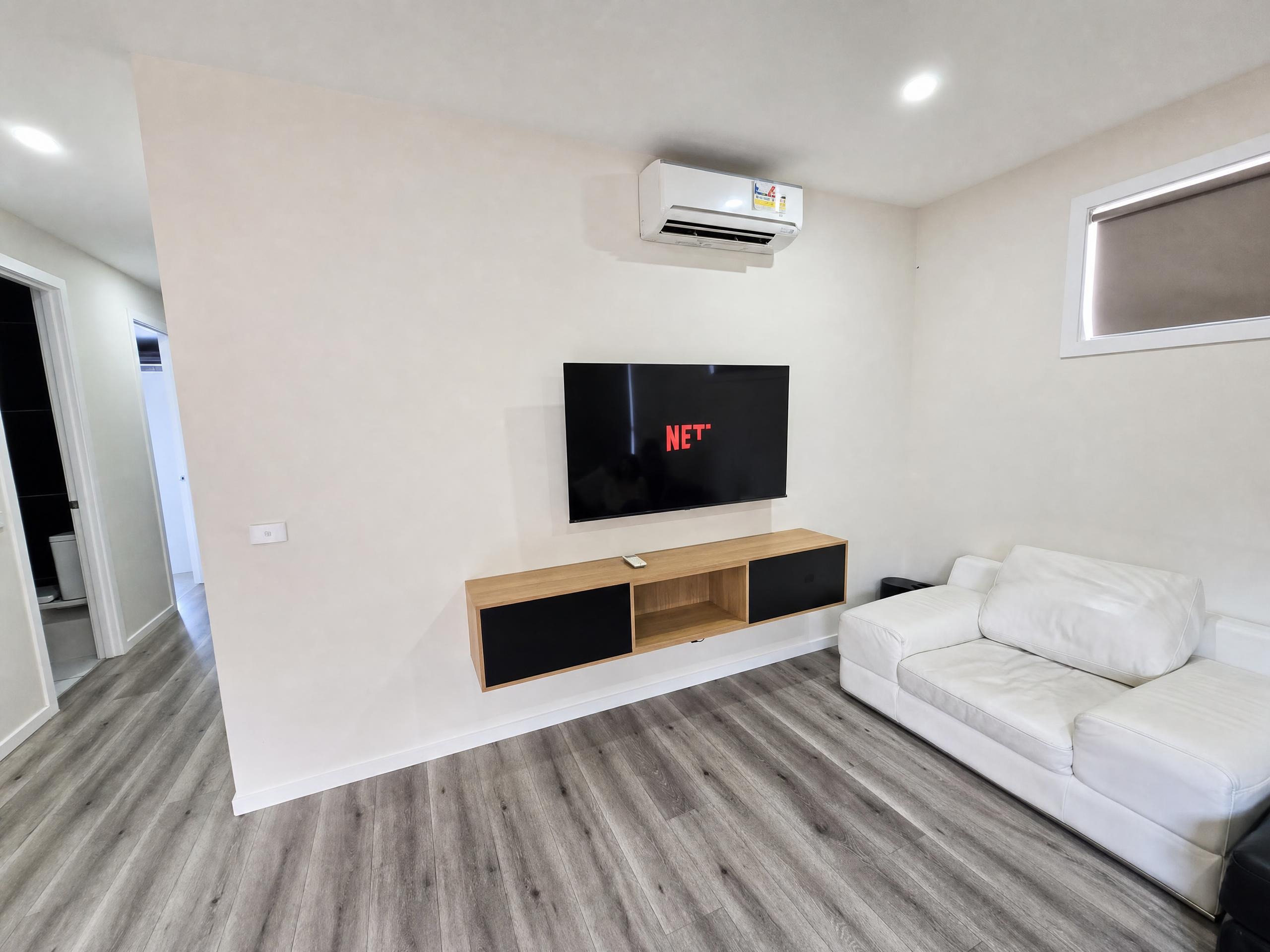 Living room with Smart TV and white sofa at Luxe Nest, 33 Maya Avenue