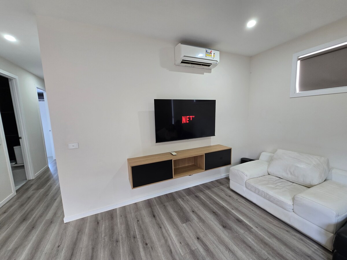 Living room with Smart TV and white sofa at Luxe Nest, 33 Maya Avenue