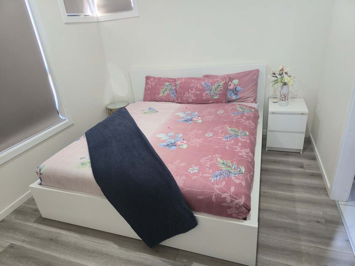 Bedroom with pink quilt and bedside tables at Luxe Nest, 33 Maya Avenue
