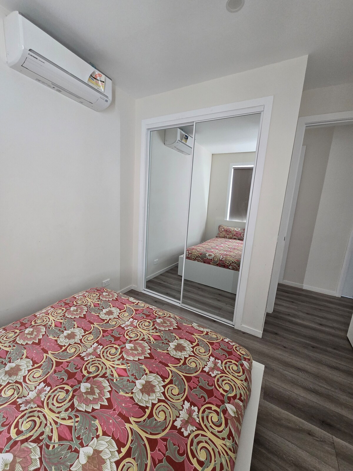 Bedroom with pink quilt and mirrored wardrobe at Luxe Nest, 33 Maya Avenue