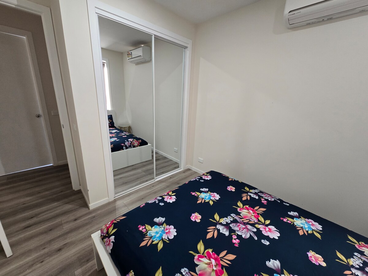 Bedroom with navy floral quilt and mirrored wardrobe at Luxe Nest, 33 Maya Avenue