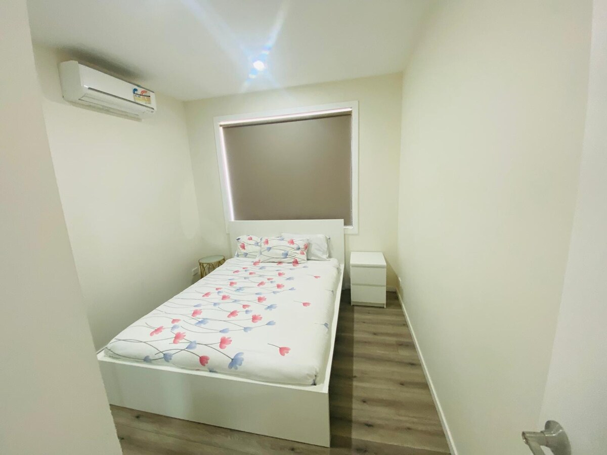 Bedroom with white patterned quilt and bedside table at Luxe Nest, 33 Maya Avenue